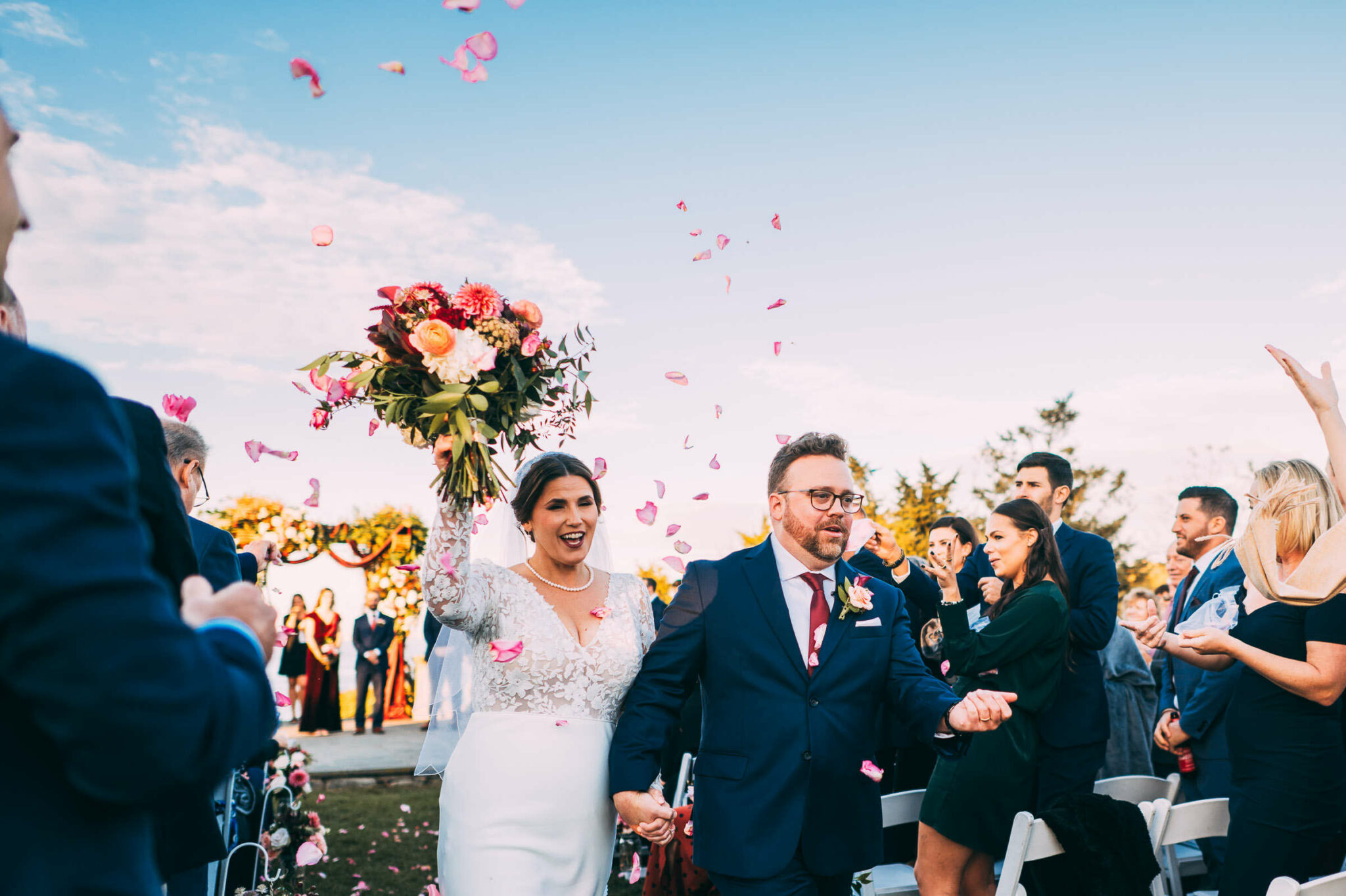 A bride and groom walk together as flower petals levitate above their heads as they exit the ceremony of their wedding at Castle Hill Inn in Newport, Rhode Island.