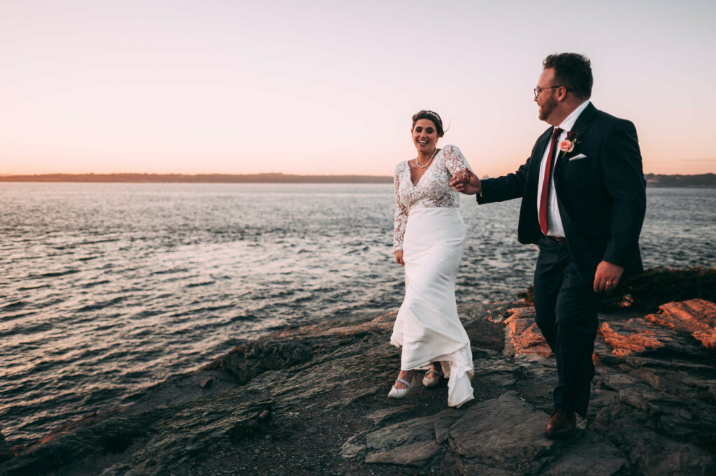 A couple walks on a cliff by the ocean during their Castle Hill Inn wedding.