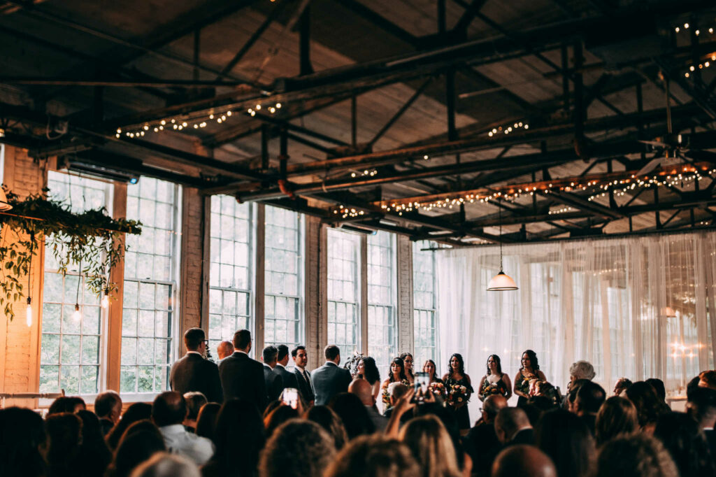 A ceremony takes place in the main hall of a Lace Factory wedding.