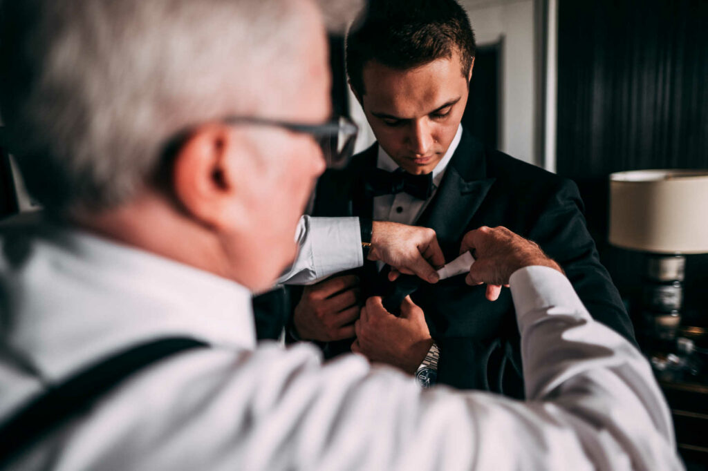 The groom receives help with his pocket square from his father before his wedding at Graduate Providence.