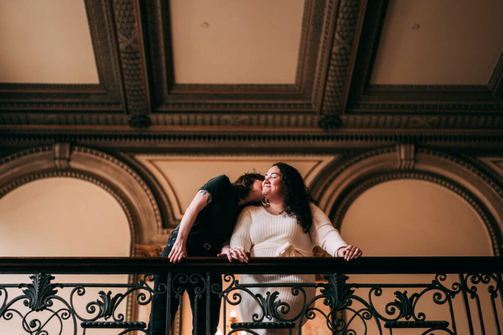 A couple enjoys their Providence engagement session while leaning over a balcony in Providence Public Library.