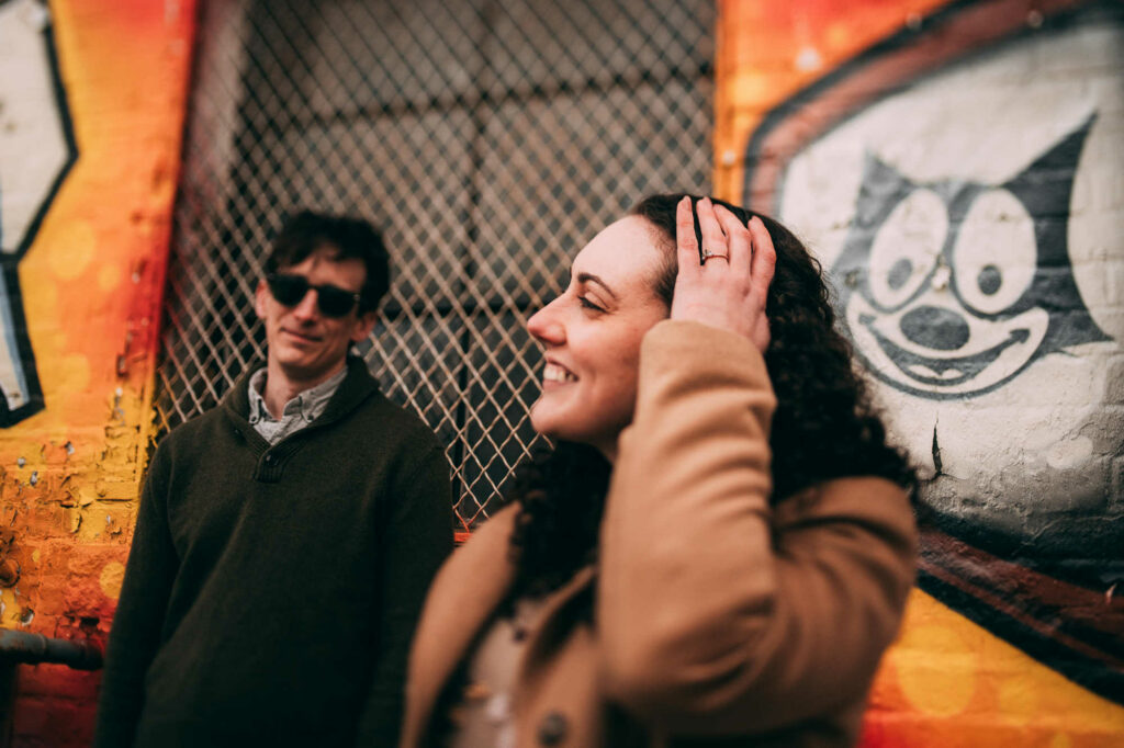 A couple poses together in front of cat graffiti during their Providence engagement session in Federal Hill.